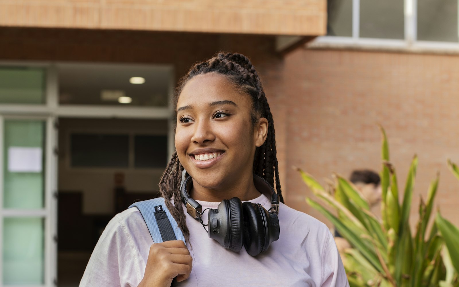 Une étudiante sac au dos, souriante, devant son établissement